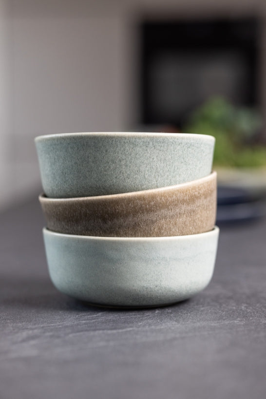 Drie opgestapelde keramieken kommen van Mimo Homeware in groenblauw en matbruin.