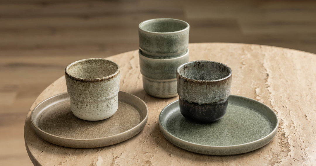 Gemixte koffiekopjes en gebaksbordjes van Mimo Homeware met natuurlijke, aardse kleuren in minimalistische stijl.