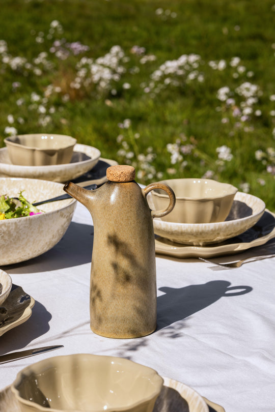 Olijfoliefles en servies op zomerse eettafel, tafelsetting in elegante stijl van Mimo Homeware.