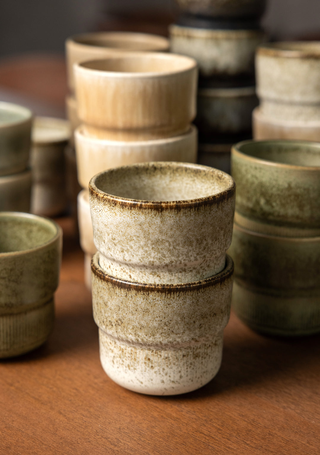 Broken Shells koffiekopje met Japandi uitstraling, omringd door minimalistische keramieken koffiekopjes in natuurlijke tinten.