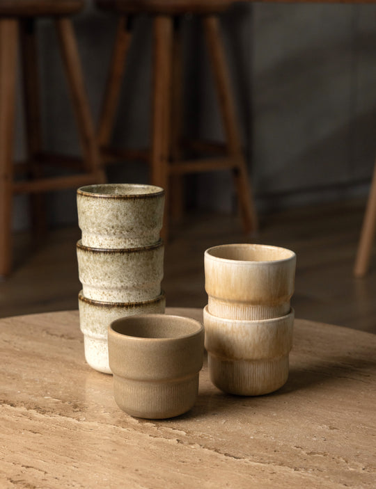 Drie lichtkleurige koffiekopjes van Mimo Homeware, in de kleuren beige, bruin en zand.