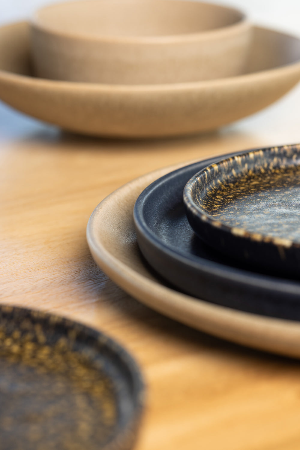 Servies van Mimo Homeware in natuurlijke kleuren, bruin servies met blauwe en zwarte borden.